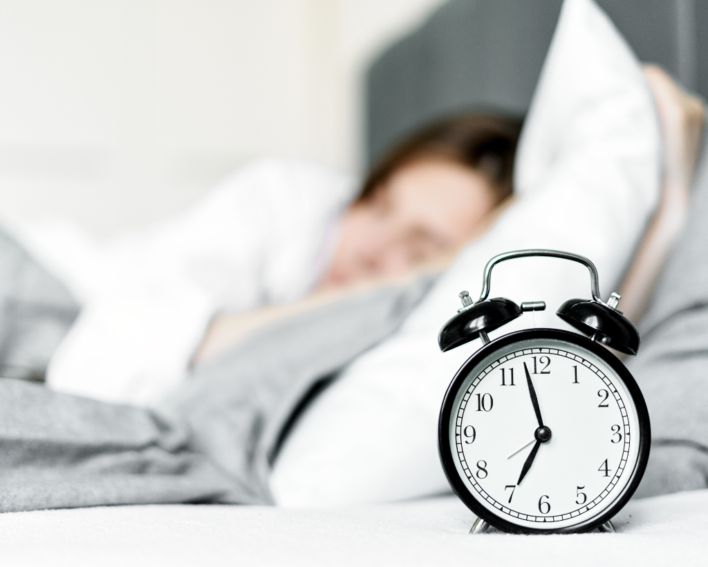 Someone Sleeping With Alarm Clock On Side Table
