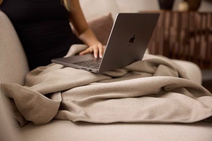 Person using a laptop and EMF blanket sitting on a couch